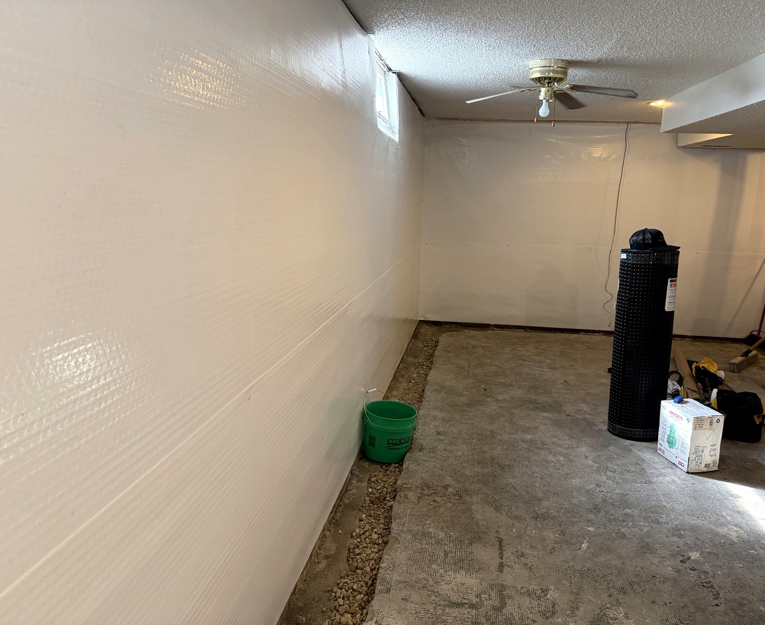 Basement waterproofing membrane and exposed drainage stone during installation