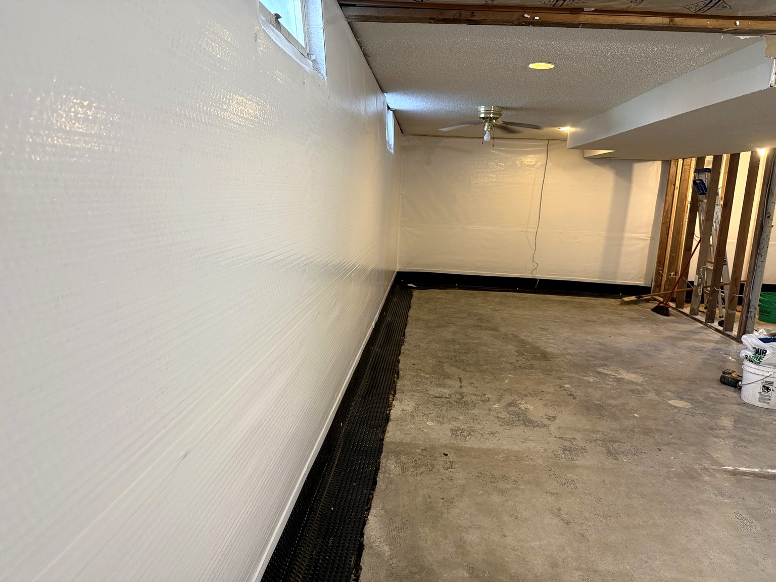 Basement interior with installed perimeter drainage channel along the wall